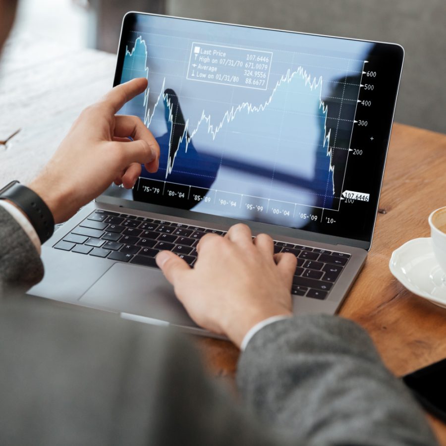 Cropped image of business man sitting by the table in cafe and analyzing indicators on laptop computer